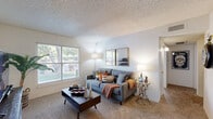 Located at 7401 Phoenix Ave in El Paso, TX, this single-story one-bedroom, one-bathroom residence offers a well-organized and functional layout across a compact but efficient floor plan. The living room serves as the heart of the home, featuring plush carpeting, textured ceilings, and large windows that invite natural light and offer views of mature trees and green outdoor surroundings. The open sightlines create a welcoming and comfortable atmosphere throughout. The combined kitchen and dining area is outfitted with cream-toned cabinetry, white appliances including a refrigerator, dishwasher, and range, along with a double-basin sink and wood-look flooring that adds warmth to the space. A dining area adjoins the kitchen, making mealtimes convenient and social. The bedroom is a relaxing retreat with soft carpeting, a window for natural light, a dedicated closet, and enough space to accommodate a full furniture arrangement. The full bathroom features a tub/shower combination with wood-look flooring and clean, neutral finishes. A hallway connects the main areas, with two closets providing practical storage solutions. Throughout the unit, the block-style wall construction adds a distinctive architectural character.