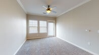 Located at 2515 W San Antonio St in New Braunfels, TX, this single-story unit offers a well-designed layout with a blend of hardwood-style and plush carpeted flooring throughout. The entryway opens into a living area with warm, neutral tones and recessed lighting, transitioning seamlessly into the galley-style kitchen. The kitchen is outfitted with dark espresso cabinetry extending to the ceiling for maximum storage, light granite countertops, a stainless steel sink, and black appliances including a full-size refrigerator. The bedrooms feature plush carpet, crown molding, ceiling fans, and window blinds that allow for natural light control. One bedroom includes a private exterior door. A dedicated in-unit laundry room houses a full-size washer and dryer with additional shelving above. The bathrooms are finished with dark vanity cabinetry, granite countertops, wood-look tile flooring, and a full tub-shower combination with white tile surround. A second bathroom offers an expansive vanity with a large mirror and ample cabinet storage. The unit's consistent use of neutral warm beige tones and quality finishes throughout creates a cohesive and comfortable living environment.