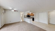 Located at 1840 Rhodes Rd in Kent, Ohio, this single-floor, 2-bedroom, 1-bathroom residence offers a practical and functional layout. The combined living and kitchen area forms the heart of the home, where a peninsula with a dark countertop separates the two spaces. The kitchen is well-equipped with warm wood cabinetry, black appliances including a refrigerator, electric range, over-the-range microwave, and dishwasher, complemented by a tile backsplash and tile flooring. The living area features plush carpeting, a ceiling fan, and a large sliding glass door dressed with vertical blinds that floods the room with natural light and provides access to the outdoors. Both bedrooms are carpeted and feature neutral white walls, windows for natural light, and baseboard heating. The primary bedroom is generously sized, offering ample room for furnishings. The full bathroom includes tile flooring, a tiled tub-and-shower combination, a single-sink vanity, and clean, functional finishes throughout. Textured ceilings are consistent across the home, adding a classic residential character to the overall space.