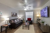 Located at 2001 Holleman Dr W in College Station, Texas, this single-story unit offers a practical and comfortable layout designed for everyday living. The open living room features wood-look flooring, a ceiling fan with light fixture, large windows that invite natural light, and ample space for seating and entertainment. The kitchen is well-equipped with white cabinetry, a full suite of white appliances including a refrigerator, electric range, and microwave, along with a double-basin sink and generous counter space. A convenient in-unit stacked washer and dryer is seamlessly integrated into the kitchen area. The bedroom is carpeted for comfort and includes a mirrored sliding-door closet with built-in shelving, a built-in desk with overhead shelving — ideal for studying or working from home — and a window that provides natural light. The bathroom features wood-look flooring, a tub-shower combination, a single-sink vanity with storage drawers, and a framed mirror. Throughout the unit, neutral tones and clean finishes create a cohesive and inviting atmosphere suited for comfortable day-to-day living.