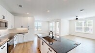 Located in Huntersville, NC, this well-appointed 2-bedroom, 2-bathroom residence offers a thoughtfully designed single-floor layout filled with modern finishes and functional living spaces. The open-concept kitchen and living area serves as the heart of the home, showcasing crisp white shaker cabinetry, dark granite countertops, stainless steel appliances, a large center island with a undermount sink, and light hardwood flooring that extends throughout the main living areas. Recessed lighting brightens the space, creating a clean, contemporary ambiance. The living room is bathed in natural light through large windows overlooking outdoor greenery. The spacious primary bedroom features plush carpeting, a ceiling fan, and direct access to a generous walk-in closet with built-in shelving and hanging rods. The primary bathroom is elegantly finished with a dual-sink white vanity, dark granite countertops, black matte fixtures, and framed mirrors. The second bedroom also offers carpet flooring, a ceiling fan, and natural light from a large window. Both bathrooms are well-appointed, with one featuring a full tub-shower combination with white tile surround and black matte hardware. A dedicated laundry room houses a full-size washer and dryer with overhead shelving for added convenience.