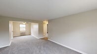 Located at 1000 Vermont Ave in Castle Shannon, PA, this single-floor residence offers a straightforward and functional layout across three bedrooms, one bathroom, and a kitchen. The living area features neutral-toned walls and plush carpeting, creating a clean and understated atmosphere. A ceiling fan and natural light from a window contribute to a comfortable ambiance, while an open passage connects the living space to the rest of the unit.

The kitchen is efficiently designed with white cabinetry, white appliances including a gas range and refrigerator, and a granite-topped breakfast bar with a pass-through window — a practical feature that connects the kitchen to the adjacent living area. Wood-style flooring anchors the kitchen space.

The spacious primary bedroom is notably generous in size, featuring two windows that bring in ample natural light and views of the surrounding neighborhood. Each bedroom is carpeted, finished in neutral tones, and equipped with classic cast-iron radiators for heating. One bedroom includes a built-in closet. The full bathroom is clean and bright, featuring a tub/shower combination, a single vanity, and a window for natural ventilation. Throughout the space, consistent neutral finishes and plush carpet flooring provide a cohesive, move-in-ready feel.