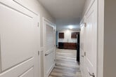This single-floor, three-bedroom, two-bathroom residence at 100 Codell Drive in Lexington, Kentucky offers a practical and well-appointed layout. Light wood-look luxury vinyl flooring runs throughout the entire unit, creating a cohesive and easy-to-maintain living environment. A central hallway connects the main living areas, lined with clean white doors—including a louvered closet door—leading to various rooms. The kitchen is a standout feature, showcasing rich dark walnut cabinetry, light granite-style countertops, a tile backsplash, and a full suite of black appliances including a refrigerator, range, microwave, and dishwasher. The kitchen opens toward the living area, providing a functional flow for daily living. Each of the three bedrooms features neutral gray walls, warm wood-tone flooring, ceiling fans with lighting, and windows that invite natural light. The primary bedroom includes direct exterior door access. Both bathrooms are finished with dark wood vanities, granite-style countertops, and wood-look flooring. One bathroom offers a full tub-shower combination with chrome fixtures and a large vanity mirror, while the second features accessible grab bars. The overall ambiance is clean, modern, and move-in ready.