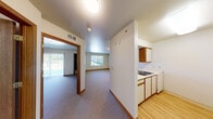 This well-organized one-bedroom, one-bathroom unit offers a practical and efficient single-floor layout designed to maximize every square foot of living space. The open central hallway connects all areas of the unit seamlessly, with carpeted flooring running through the living and bedroom areas and hard surface flooring in the kitchen and bathroom.

The kitchen is positioned off the main corridor and features wood-trimmed white cabinetry providing ample storage, a white coil-burner electric range with an overhead exhaust hood, a double sink, and a dishwasher — all arranged for functional daily use.

The living area is bright and welcoming, with natural light streaming in through multiple windows. A sliding glass door fitted with vertical blinds opens to an outdoor view, enhancing the sense of openness in the space.

The bedroom is a comfortable, well-proportioned room with carpeted flooring, a sliding door to the outdoors, and access to a dedicated closet for storage.

The bathroom is clean and functional, featuring a wide vanity with a white countertop, wood-accented cabinetry, a large mirror with overhead lighting, tile flooring, and a wall-mounted grab bar, reflecting thoughtful and accessible design.

Throughout the unit, consistent wood-tone trim, textured ceilings, and neutral wall tones create a cohesive and understated aesthetic.