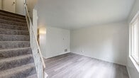 This two-story, two-bedroom, two-bathroom home in Dayton, Ohio offers a well-organized layout spread across two floors. The main level features a kitchen equipped with dark cabinetry, granite-style countertops, stainless steel appliances including a range, microwave, and dishwasher, complemented by a range hood and light wood-style vinyl flooring. Natural light filters through windows, lending a bright and airy feel to the cooking and dining area. A staircase with white balusters connects the main level to the upper floor, where the living area showcases clean, neutral walls and the same light wood-style flooring. Both bedrooms are comfortably sized, each featuring built-in closets with hanging rods for ample storage. The primary bedroom offers a generous footprint with a window that brings in natural light and views of the surrounding greenery. The two bathrooms are finished in a clean, modern style, with one featuring a full tub-shower combination, a vanity with a white countertop, and wood-style flooring. Throughout the home, the consistent use of light, neutral tones and updated finishes creates a cohesive and move-in-ready atmosphere.