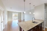 Located at 346 Turnpike Rd in Westborough, MA, this well-appointed one-bedroom, one-bathroom residence offers a thoughtfully designed single-floor layout. The open-concept kitchen and living area serves as the heart of the home, featuring rich dark-cabinetry, granite countertops, a central kitchen island with a built-in sink, and stainless steel appliances including a refrigerator, range, and microwave. Three pendant lights hang above the island, adding a polished touch. Hardwood flooring flows throughout the main living areas, complementing the neutral-toned walls and creating a warm, cohesive aesthetic. Sliding glass doors in the living room invite natural light and provide access to an outdoor area. A dedicated office space and dining area offer functional versatility. The generously sized bedroom features plush carpeting, a bright window with outdoor views, and access to a large walk-in closet with wire shelving. The full bathroom is finished with classic white subway tile surrounding the soaking tub and shower, large-format floor tiles, a dark wood vanity, and brushed nickel fixtures. Additional conveniences include a laundry room, utility room, entrance foyer, and two closets, rounding out this complete and functional residence.