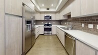 Located at 928 N Western Ave in the heart of Los Angeles, unit 308 is a thoughtfully designed single-floor residence that blends contemporary finishes with functional living. Throughout the unit, warm wood-style flooring ties the spaces together, complemented by crisp white walls and recessed lighting that create a clean, modern aesthetic.

The open living area is generously proportioned, offering flexible arrangement possibilities, and features a sliding glass door that opens directly onto a private balcony with views of the surrounding neighborhood, including glimpses of palm trees and the Los Angeles skyline. Natural light flows freely through large windows.

The kitchen is well-appointed with light wood cabinetry, white quartz countertops, a textured tile backsplash, and a full suite of stainless steel appliances, including a gas range, built-in microwave, refrigerator, and dishwasher — all set beneath recessed lighting in a coffered ceiling detail.

The bedrooms are spacious and bright, each with ample closet space, including a walk-in closet with built-in shelving. Two bathrooms serve the unit: one features a combination tub and glass-enclosed shower with wood-toned cabinetry, while the second offers a standalone glass-enclosed shower with large-format tile and a sleek vanity.