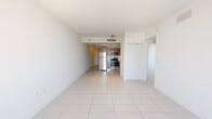 Located at 1900 Southwest 8th Street in Miami's vibrant Little Havana neighborhood, this two-bedroom, one-bathroom residence offers a bright and functional layout across a single floor. The interior is finished with large-format white ceramic tile flooring throughout, contributing to a clean, cohesive aesthetic that reflects natural light effectively.

The open-plan kitchen and living area serves as the heart of the home. The kitchen is equipped with stainless steel appliances — including a refrigerator, range, and built-in microwave — complemented by warm wood-tone cabinetry, a tile backsplash, and light countertops. A dedicated laundry area adds everyday convenience.

A hallway connects the main living spaces to the two bedrooms and full bathroom. The primary bedroom is generously sized, featuring a large window with views of the surrounding Miami skyline and tree canopy, filling the room with natural light. The second bedroom offers a clean, open layout with the same tile flooring. Both bedrooms are served by louvered bi-fold closet doors, providing practical storage. The full bathroom includes a tub/shower combination with a curved rod, a vanity, and tile flooring. The entrance foyer provides a welcoming transition into the home.