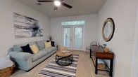 Located at 9525 US-78 Highway in Ladson, South Carolina, this single-floor residential unit offers a thoughtfully designed layout with comfortable living spaces throughout. The living room is bright and airy, featuring a ceiling fan, plush carpeting, and French doors that open to views of lush greenery, allowing natural light to fill the room. A striped area rug and neutral walls contribute to the relaxed, welcoming ambiance.

The kitchen is clean and functional, finished with white cabinetry, tile flooring, and a full suite of white appliances including a refrigerator, range, and built-in microwave. A breakfast bar with seating for two provides a casual dining option. Conveniently, an in-unit laundry closet is accessible directly from the kitchen.

The unit includes two carpeted bedrooms, each with windows overlooking wooded surroundings, providing a serene and private atmosphere. Both bathrooms feature tile flooring, vanities with ample counter space, and shower/tub combinations.

The community clubroom is a standout amenity, offering a spacious gathering area with a fireplace, built-in bookshelves with decorative millwork, large windows, French doors, ceiling fan, and a seating arrangement that encourages relaxation and socializing. The overall design of the property balances practicality with comfort in a convenient Ladson location.