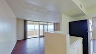 This thoughtfully designed residence spans a comfortable single floor, featuring 2 bedrooms, 3 bathrooms, a combined kitchen and living area, a hallway, and a dedicated closet. The open living room is a standout space, showcasing rich hardwood flooring, a textured ceiling, and expansive floor-to-ceiling sliding glass doors and French doors that lead to a balcony, filling the room with natural light and offering open outdoor views. A partial wall divides the living area from the kitchen, which is well-equipped with white cabinetry, tile backsplash, a stainless steel wall oven, a cooktop, and light tile flooring.

The spacious primary bedroom features plush carpeting and direct balcony access through sliding glass doors, while the second bedroom also offers carpeted floors and ample room. A generous walk-in closet is outfitted with built-in shelving and tile flooring. The three bathrooms are finished with light tile floors; one includes a dark granite vanity countertop with a tub-shower combination, while another features a separate shower and tub. Overall, the residence maintains a bright, neutral palette throughout.