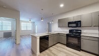 This single-story, three-bedroom, three-bathroom home in Austin, TX offers a well-designed layout with modern finishes throughout. The open-concept kitchen and living area serves as the heart of the home, featuring granite countertops, a peninsula with pendant lighting overhead, gray cabinetry, and black appliances including a range, microwave, dishwasher, and refrigerator. A stainless steel sink is integrated into the peninsula, adding both style and functionality. Light wood-style flooring flows seamlessly through the main living areas, complementing the neutral color palette and recessed lighting above. The living room benefits from natural light through windows fitted with blinds, and a ceiling fan adds comfort to the space. Each of the three bedrooms offers a calm, neutral environment with the same wood-style flooring and windows that invite natural light. The primary bathroom includes a granite-topped vanity, built-in shelving, and access to a walk-in closet with wire shelving. Additional bathrooms feature tub-shower combinations with clean, white surrounds. The home also includes a dedicated closet for added storage, rounding out a practical and comfortable living space.