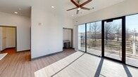 Located at 627 Emma Ave in Springdale, Arkansas, this well-appointed 2-bedroom, 2-bathroom residence offers a thoughtfully designed single-floor layout. The open-concept kitchen and living area serves as the heart of the home, showcasing a large granite-topped island with an undermount sink, gray shaker-style cabinetry, a white subway tile backsplash, stainless steel appliances, and stylish pendant lighting. Light wood-look flooring flows throughout, complementing the clean, bright white walls.

The primary bedroom is generously sized, featuring soaring ceilings, a ceiling fan, and dramatic floor-to-ceiling sliding glass doors that open to a private balcony with outdoor views — flooding the space with natural light. A built-in desk area adds functional convenience. The second bedroom also benefits from elevated ceilings and its own ceiling fan. Both bathrooms are finished with granite vanity tops and dark cabinetry with brushed nickel hardware.

Additional highlights include three closets for ample storage, a dedicated laundry area, and a central hallway connecting the rooms efficiently. An accessible electrical panel is tucked neatly into the hallway wall. The overall aesthetic is modern and clean, with consistent finishes creating a cohesive and polished living environment.