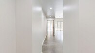 This contemporary 3-bedroom, 2-bathroom residence showcases a thoughtfully designed single-floor layout with a clean, modern aesthetic throughout. Polished concrete floors unify the living spaces, complemented by crisp white walls and exposed concrete beams that lend an industrial-chic character to the interior.

The open living area benefits from floor-to-ceiling windows that flood the space with natural light and offer views of the surrounding urban streetscape. A sliding wood-panel door connects the living area to the rest of the unit, adding a warm architectural detail against the neutral palette.

The kitchen is well-equipped and features warm wood cabinetry, dark granite countertops, a marble-style tile backsplash, and stainless steel appliances including a range, microwave, and dishwasher — ideal for everyday cooking and entertaining.

Both bathrooms are finished with dark granite vanity countertops atop warm wood cabinetry, slate-toned tile flooring, illuminated mirrors, and marble-surround soaking tubs with overhead showers. The primary bedroom is generously sized and benefits from abundant natural light. Two dedicated closets with built-in wire shelving provide ample storage. The unit's cohesive design blends industrial elements with refined finishes throughout.