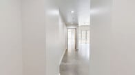 This contemporary 3-bedroom, 2-bathroom residence showcases a thoughtfully designed single-floor layout with a clean, modern aesthetic throughout. Polished concrete floors unify the living spaces, complemented by crisp white walls and exposed concrete beams that lend an industrial-chic character to the interior.

The open living area benefits from floor-to-ceiling windows that flood the space with natural light and offer views of the surrounding urban streetscape. A sliding wood-panel door connects the living area to the rest of the unit, adding a warm architectural detail against the neutral palette.

The kitchen is well-equipped and features warm wood cabinetry, dark granite countertops, a marble-style tile backsplash, and stainless steel appliances including a range, microwave, and dishwasher — ideal for everyday cooking and entertaining.

Both bathrooms are finished with dark granite vanity countertops atop warm wood cabinetry, slate-toned tile flooring, illuminated mirrors, and marble-surround soaking tubs with overhead showers. The primary bedroom is generously sized and benefits from abundant natural light. Two dedicated closets with built-in wire shelving provide ample storage. The unit's cohesive design blends industrial elements with refined finishes throughout.