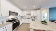 Located at 2300 N Broad St in Fuquay-Varina, NC, this thoughtfully designed single-story home offers two bedrooms, two bathrooms, and a well-appointed layout across a comfortable footprint. The open-concept kitchen is a standout feature, showcasing crisp white shaker cabinetry, subway tile backsplash, granite countertops, stainless steel appliances including a range, microwave, dishwasher, and refrigerator, and a central island with bar seating and built-in shelving — all set atop durable wood-look flooring. The living room provides a welcoming gathering space with a ceiling fan, natural light from large windows, and direct access to the exterior. Both bedrooms are carpeted and filled with natural light from generous windows. The primary bedroom includes a walk-in closet with wire shelving, and its en-suite bathroom features a granite-topped vanity and wood-look flooring. A second well-sized closet serves the secondary bedroom. The dedicated laundry room houses a full-size top-loading washer and dryer with overhead shelving. Clean lines, neutral tones, and modern finishes throughout give this home a fresh, cohesive aesthetic ideal for comfortable everyday living.
