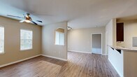 This thoughtfully designed single-floor residence offers a comfortable and functional layout across its well-proportioned living spaces. The open-concept living room features warm hardwood-style flooring, neutral beige walls, a ceiling fan, and an elegant arched pass-through window with track lighting, adding a distinctive architectural touch. Multiple windows fitted with blinds allow natural light to fill the space throughout the day.

The galley-style kitchen is outfitted with rich dark espresso cabinetry, granite-look countertops, a stainless steel sink, and black appliances including a range, built-in microwave, dishwasher, and refrigerator. A breakfast bar provides additional counter space and casual seating. Track lighting overhead ensures excellent task visibility.

The generously sized bedroom is carpeted for comfort and includes a ceiling fan, ample natural light from dual windows, and convenient access to a dedicated walk-in closet with built-in shelving. The full bathroom features matching dark wood cabinetry, a single vanity with a light bar and mirror, and hardwood-style flooring. A separate laundry room accommodates a full-size washer and dryer with additional overhead shelving, completing this practical and well-finished home.