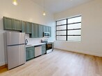 This well-appointed one-bedroom, one-bathroom unit at 300 Benedict Dr in Pittsburgh, PA offers a cohesive and modern living experience across a single floor. Light hardwood flooring flows seamlessly throughout, tying together each room with warmth and consistency.

The open-concept kitchen, dining, and living area serves as the heart of the home, immediately impressing with soaring ceilings and a striking large industrial-style window that frames abundant natural light. The kitchen features sage green cabinetry with brass hardware, a white subway tile backsplash, light countertops, and a full suite of stainless steel appliances including a refrigerator, electric range, microwave, and dishwasher. Pendant lighting adds a refined touch above the kitchen space.

The bedroom is a comfortable, private retreat with mirrored sliding closet doors that enhance the sense of space, along with an additional separate closet for ample storage. A hallway connects the living areas to the bedroom, bathroom, and laundry.

The bathroom is elegantly finished with marble-look tile flooring, a green vanity with a white countertop and matte black fixtures, warm wood-toned accent wall, a full bathtub and shower, and recessed lighting, creating a clean and spa-like feel.

A dedicated laundry area adds everyday convenience to this thoughtfully designed Pittsburgh residence.