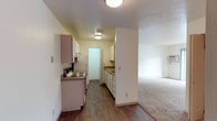 Located at 12202 East Maxwell Avenue in Spokane, Washington, this single-floor residence offers a functional and comfortable layout throughout. The galley-style kitchen is equipped with ample upper and lower cabinetry, laminate countertops, an electric range, and a full-size refrigerator, all set atop durable hardwood-style flooring. The kitchen connects seamlessly to the adjacent living area, which is finished with neutral wall-to-wall carpeting and features a sliding glass door that opens to a private balcony overlooking mature trees, allowing natural light to fill the space. The bedrooms are generously sized, each finished with plush carpet, baseboard heating, and easy closet access. One bedroom benefits from a window with an outdoor view, further enhancing the sense of natural light. The unit includes two full bathrooms, each outfitted with a tub-shower combination, a vanity with a countertop sink, and a wall mirror. Textured ceilings are present throughout, adding a classic character to the home. The entry area features hardwood-style flooring, providing a clean and practical transition into the carpeted main living spaces. Overall, the residence presents a clean, straightforward layout well-suited for everyday living.