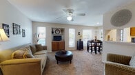 This single-floor residence at 735 Residenz Pkwy in Kettering, Ohio offers a well-organized layout across several distinct living areas. The living room serves as the central gathering space, featuring neutral carpet, a ceiling fan with light fixture, and multiple windows that allow ample natural light. A built-in wall niche with wood cabinetry below provides a dedicated media and display area, adding a functional architectural detail to the room.

The dining area is positioned adjacent to the living space, benefiting from additional windows that bring in exterior views and natural light. A separate flex room with carpet flooring offers versatility as a home office or secondary living space.

The galley-style kitchen is efficiently arranged with warm wood cabinetry lining both sides, light-tiled flooring, and includes a range, refrigerator, dishwasher, and double sink. A hallway connects the kitchen to the rest of the unit.

The bedroom is a comfortable retreat with carpet flooring, a ceiling fan, a window with natural light, and direct access to a walk-in closet with built-in shelving. The bathroom features tile flooring and connects conveniently to the hallway. Throughout, the residence maintains a consistent neutral palette and carpet-focused flooring scheme.