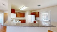 This well-appointed 2-bedroom, 1-bathroom single-story residence offers a functional and comfortable layout across its single floor. The kitchen serves as a central highlight, featuring rich warm-toned wood cabinetry extending to the upper and lower walls, granite-style countertops, and a peninsula that opens to the adjoining living area. White appliances including a range, microwave, dishwasher, and refrigerator are neatly integrated into the kitchen design. Natural light enters through a window near the kitchen, enhancing the open feel of the shared living space, which is equipped with a ceiling fan.

The two bedrooms are bright and functional, each featuring hardwood-style flooring, neutral wall tones, and windows fitted with blinds that allow for natural light and privacy. The primary bedroom includes access to a dedicated closet with built-in shelving, providing organized storage. The second bedroom also features a ceiling fan for added comfort.

The bathroom is clean and efficiently designed, with tile flooring, a sliding glass-door shower enclosure, a toilet, and a wall-mounted sink. Grab bars add a practical, accessible touch. Two hallways and two closets round out the layout, ensuring smooth circulation and ample storage throughout this tidy, move-in-ready home.