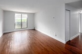 Located at 100 Old Carriage Dr in Kitchener, Ontario, this 2-bedroom, 1-bathroom unit offers a functional and comfortable layout spread across a single floor. Warm hardwood flooring flows consistently throughout the space, complementing the neutral grey and white tones that give each room a clean, bright aesthetic.

The living room is a generous, open space filled with natural light from a large window overlooking lush greenery, creating a calm and inviting atmosphere. It connects naturally to the kitchen, which features crisp white cabinetry, light stone countertops, and a full suite of stainless steel appliances including a refrigerator, electric range, and built-in microwave — ideal for everyday cooking.

A central hallway leads to both bedrooms, each finished with the same rich hardwood flooring and soft neutral walls. The primary bedroom offers a comfortable footprint with a closet, while the second bedroom also benefits from a window with pleasant outdoor views and a baseboard heating unit. The bathroom is finished with large-format grey tile surrounding a full soaker tub and shower, paired with a clean white toilet and sink vanity.

The unit's layout is efficient and practical, with well-defined rooms and consistent finishes throughout, making it a functional residential space in a quiet Kitchener neighbourhood.