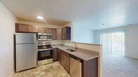 Located at 2040 Taylor Road in Auburn Hills, Michigan, this single-floor, one-bedroom, one-bathroom residence offers a thoughtfully designed layout that maximizes functionality and comfort. The open-concept kitchen, dining, and living area forms the heart of the home, with the kitchen showcasing rich, medium-toned wood cabinetry, granite countertops, a stainless steel appliance suite including a refrigerator, range, microwave, and dishwasher, and durable tile flooring. A peninsula with a double sink opens the kitchen toward the carpeted living and dining area, promoting a connected, airy feel. Vertical blinds on the sliding door provide access to a private balcony, bringing in natural light. The bedroom is a comfortable retreat finished with plush carpet, a window overlooking greenery, and access to two closets — one of which is a walk-in with built-in shelving. The combined bathroom and laundry room is finished with granite countertops, warm wood cabinetry, tile flooring, and accessibility-friendly grab bars throughout. The entryway provides a welcoming transition with tile flooring and an electrical panel nearby. The overall palette of neutral tones and consistent finishes gives this residence a clean, move-in-ready character.