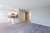 This two-floor residence offers a well-organized layout designed for comfortable everyday living. The main level centers around an open-concept living and dining area finished with plush, neutral-toned carpet, which flows seamlessly into a functional kitchen. The kitchen features white shaker-style cabinetry, dark speckled countertops, wood-look flooring, and a full suite of stainless steel appliances including a refrigerator, microwave, and range. A peninsula counter provides additional workspace and separates the kitchen from the living area. A staircase leads to the upper level, where the bedrooms are located. Each bedroom is carpeted, painted in soft gray tones, and includes windows that bring in natural light and views of the surrounding greenery. One bedroom features sliding closet doors with generous storage space. The bathrooms are consistently finished with white cabinetry, dark countertops, and large mirrors, contributing to a clean and cohesive aesthetic. A full bathroom on the upper level includes a shower and vanity, while an additional bathroom provides further convenience. Textured ceilings are present throughout the home. The overall ambiance is clean, neutral, and move-in ready, offering a practical and comfortable living environment.