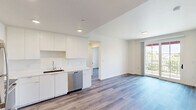 Located at 425 Garden St in the heart of Santa Barbara, California, this thoughtfully designed 2-bedroom, 2-bathroom residence offers a clean, modern aesthetic across a single level of living space. Light wood-tone flooring flows consistently throughout, complementing the crisp white walls and contemporary finishes that define the unit's style.

The kitchen is well-appointed with white flat-front cabinetry extending to the ceiling, a white countertop with an undermount sink, and a full suite of stainless steel appliances including a refrigerator, range, microwave, and dishwasher. Recessed lighting adds a polished touch to this functional space.

The primary bedroom features a large sliding glass door that opens to a private balcony, offering sweeping views of the Santa Barbara treetops, palm trees, and mountains beyond under sunny California skies. A second bedroom provides ample natural light through a bright window overlooking lush greenery, along with a built-in sliding door closet for storage.

Both bathrooms mirror each other in design, each featuring a white vanity with an integrated sink, a framed mirror, and a shower area, all finished with the same warm wood-look flooring. The hallway connects all rooms efficiently, maintaining a cohesive and functional layout throughout this contemporary Santa Barbara residence.