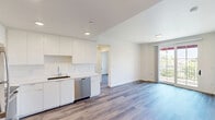 Located at 425 Garden St in the heart of Santa Barbara, California, this thoughtfully designed 2-bedroom, 2-bathroom residence offers a clean, modern aesthetic across a single level of living space. Light wood-tone flooring flows consistently throughout, complementing the crisp white walls and contemporary finishes that define the unit's style.

The kitchen is well-appointed with white flat-front cabinetry extending to the ceiling, a white countertop with an undermount sink, and a full suite of stainless steel appliances including a refrigerator, range, microwave, and dishwasher. Recessed lighting adds a polished touch to this functional space.

The primary bedroom features a large sliding glass door that opens to a private balcony, offering sweeping views of the Santa Barbara treetops, palm trees, and mountains beyond under sunny California skies. A second bedroom provides ample natural light through a bright window overlooking lush greenery, along with a built-in sliding door closet for storage.

Both bathrooms mirror each other in design, each featuring a white vanity with an integrated sink, a framed mirror, and a shower area, all finished with the same warm wood-look flooring. The hallway connects all rooms efficiently, maintaining a cohesive and functional layout throughout this contemporary Santa Barbara residence.