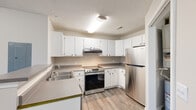 Located at 1605 E Hines St in Republic, Missouri, Unit C204 is a thoughtfully designed single-floor residence that combines functional living spaces with clean, modern finishes throughout. The kitchen is a standout feature, equipped with stainless steel appliances including an electric range and refrigerator, crisp white cabinetry offering ample storage, laminate countertops, and a stainless steel sink. Light wood-look vinyl plank flooring ties the kitchen together with a fresh, contemporary feel. The open living area extends the sense of space, featuring the same wood-look flooring, neutral wall tones, a ceiling fan, and French doors that invite natural light into the room. An additional open area provides flexible space, also finished with wood-look plank flooring and soft neutral walls. The bedrooms are carpeted for comfort, each featuring ceiling fans, natural light from windows with blinds, and closet space — one bedroom includes a dedicated walk-in closet. The bathroom is finished with a white vanity, laminate countertop, and brushed nickel fixtures beneath a well-lit vanity mirror. A dedicated in-unit laundry closet houses a full-size washer and dryer, adding everyday convenience. Textured ceilings are consistent throughout the unit, contributing to its classic residential character.