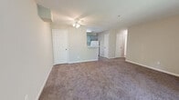 Located at 46910 Shady Point Sq in Sterling, VA, this single-floor residence offers three bedrooms and two bathrooms within a practical and well-organized layout. The living room serves as the central gathering space, finished with plush wall-to-wall carpeting and a ceiling fan, and opens directly to a private balcony through sliding glass doors. The balcony overlooks a dense canopy of mature trees, providing a serene, nature-filled backdrop. The kitchen features a galley-style design with grey cabinetry, white quartz-style countertops, white appliances including an electric range and refrigerator, and light wood-look flooring — offering efficient use of space and a clean aesthetic. A louvered door leads to an in-unit laundry area. The three bedrooms are carpeted and receive natural light through double windows that frame views of surrounding greenery. The primary bedroom is a comfortable, well-proportioned retreat. Both bathrooms are finished with light wood-look flooring, grey vanity cabinetry, and white fixtures; one includes a full tub-shower combination. Neutral wall tones throughout the home create a cohesive and move-in-ready environment.