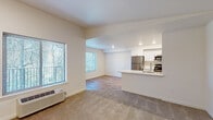 This single-floor residence presents a clean, contemporary design throughout its well-organized layout. The open-concept living area is anchored by neutral-toned carpet and benefits from multiple windows that invite natural light and offer views of surrounding greenery. A wall-mounted climate control unit provides convenient temperature management. The kitchen connects seamlessly to the living space via a peninsula counter with a white quartz surface, making it ideal for both meal preparation and casual interaction. White shaker-style cabinetry lines the kitchen walls, complemented by stainless steel appliances including a refrigerator, microwave, range, and dishwasher, all set above light wood-tone flooring. A dedicated laundry area features matching white cabinetry, a utility sink, and ample counter space. The bedrooms are carpeted and well-proportioned, each featuring closets with built-in shelving and windows for natural light. Two full bathrooms are finished with warm stone-look tile flooring, white vanities with brushed nickel hardware, and tub-shower combinations. The overall palette of crisp whites and neutral tones gives the space a fresh, move-in-ready appearance.