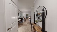 This thoughtfully designed 2-bedroom, 2-bathroom single-story residence offers a seamless open-concept layout connecting the kitchen, dining, and living areas. The kitchen is a standout feature, showcasing rich dark-stained cabinetry, dark granite countertops, stainless steel appliances including a full-size refrigerator, a black electric range, and built-in microwave. A peninsula with bar seating and elegant pendant lighting bridges the kitchen to the dining and living spaces. Crown molding is found throughout, lending a refined architectural detail to every room. The living room is bright and welcoming, with large windows providing natural light and plush carpeting underfoot. The dedicated dining area offers an intimate setting ideal for entertaining. Both bathrooms feature dark wood vanities, granite countertops, framed mirrors, and hardwood-style flooring. The primary bedroom is generously sized, highlighted by a bold accent wall and a large window with outdoor views. The second bedroom mirrors this comfortable aesthetic. A dedicated laundry room with full-size washer and dryer hookups, hardwood-style floors in key areas, and a walk-in closet round out the practical and polished features of this well-equipped residence.