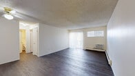 This 2-bedroom, 2-bathroom unit in Lakewood, Colorado offers a practical and comfortable single-floor layout. Dark hardwood-style flooring runs consistently throughout the space, providing a clean, cohesive look against the neutral, light-toned walls. The living room is a generously open area featuring large vertical-blind-covered sliding doors that invite natural light, complemented by a wall-mounted air conditioning unit and baseboard heating. A dedicated entrance and hallway connect the living areas to the private quarters of the home. The kitchen is laid out efficiently in a galley style, equipped with light wood cabinetry, a double basin sink, electric coil range, dishwasher, and refrigerator, along with a window that brings in additional natural light. Both bedrooms are well-proportioned, each featuring windows with vertical blinds, baseboard heating, and textured ceilings. The primary bedroom is notably spacious and includes a dedicated closet. Each of the two bathrooms is outfitted with a full tub and shower combination, with one bathroom offering a wide vanity featuring light wood cabinetry and a large mirror. Two closets throughout the unit provide ample storage for residents.