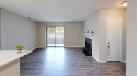 This single-floor residence in Durham, NC offers a well-organized layout across two bedrooms and one bathroom. The open-concept living and kitchen area forms the heart of the home, where wood-look laminate flooring extends throughout. The kitchen features a galley-style design with white cabinetry, light countertops, stainless steel appliances including a range and refrigerator, and a peninsula with a built-in sink that opens toward the living area, making it functional for both cooking and entertaining.

The living room is a standout space, highlighted by a tile-surround fireplace with a white mantel and a full-width sliding glass door that fills the room with natural light and provides outdoor access. Neutral wall tones and textured ceilings are consistent throughout.

The primary bedroom is generously sized, featuring carpet flooring, two closets, and a window with outdoor views. The second bedroom also includes carpet, a closet, and natural light from a window. Both bedrooms offer a quiet, comfortable feel.

The bathroom is clean and efficiently laid out with a tub-shower combination, white tile surround, a single-sink vanity with white cabinetry, and wood-look flooring that ties into the rest of the home's design.