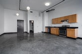 Located in the heart of Downtown Los Angeles, this loft-style unit at 620 S Main St offers a compelling blend of industrial character and modern convenience. The open-plan main living area is defined by soaring ceilings, polished concrete floors, and a wall of floor-to-ceiling windows fitted with roller shades, flooding the space with natural light and framing dynamic urban views of the surrounding cityscape. Industrial-style track lighting and exposed pipe accents along the ceiling reinforce the loft aesthetic throughout.

The kitchen is integrated seamlessly along one wall, featuring warm maple cabinetry with dark countertops, a stainless steel gas range with overhead ventilation, a built-in dishwasher, and a double-basin sink — providing a fully functional cooking space without interrupting the open flow of the unit. A louvered closet door and in-unit washer provide added practicality.

The bathroom is finished with classic black-and-white tiled walls in a bold checkerboard pattern, complemented by a pedestal sink, a full bathtub with shower, and dark tile flooring, offering a clean and timeless aesthetic. The unit's single-floor layout maximizes usability, and its location places residents steps from the best of Downtown LA's dining, arts, and transit amenities.