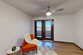 Located at 6775 N 67th Ave in Glendale, Arizona, this single-story 2-bedroom, 1-bathroom residence offers a clean, modern design with consistent wood-look flooring throughout. The living room is a bright, welcoming space anchored by a ceiling fan with light fixture and a set of bold double doors with glass panels that invite natural light and provide outdoor views. The open layout creates a comfortable sense of space ideal for everyday living. The kitchen is a standout feature, showcasing warm walnut-toned cabinetry extending to the ceiling for ample storage, light countertops, and a full suite of white appliances including a range, microwave, dishwasher, and refrigerator. Recessed lighting illuminates the space efficiently. Both bedrooms are well-proportioned, each equipped with a ceiling fan and light fixture, and feature access to closet space. The rooms maintain a clean, neutral palette with light walls and dark baseboards for a contemporary contrast. The bathroom includes a full-size tub and shower combination with built-in shelving and clean white surrounds. Throughout the residence, the cohesive use of light flooring, neutral tones, and modern fixtures creates a bright and functional living environment.