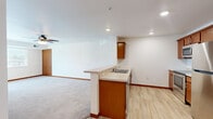 Located at 19568 Station St in Big Lake, MN, this 2-bedroom, 1-bathroom single-floor residence offers a well-designed layout that maximizes comfort and functionality. The open-concept kitchen and living area form the heart of the home, with the kitchen featuring warm medium-toned wood cabinetry, stainless steel appliances including a refrigerator, range, and built-in microwave, and a peninsula with a double sink that seamlessly connects to the living space. Light wood-look flooring runs through the kitchen, while plush carpet covers the living area and bedrooms, providing a cozy feel throughout. The spacious primary bedroom includes a ceiling fan, a large window for natural light, and a closet, while the second bedroom also benefits from a bright window with outdoor views. Warm wood-toned doors and baseboards add a consistent design element across all rooms. A glass-panel door in the living area opens to a private balcony overlooking a green outdoor setting. The bathroom is finished with a full soaking tub and shower combination. Recessed lighting throughout the main living areas ensures a clean, modern aesthetic in this efficiently designed home.