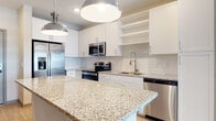 Located at 7950 Park Blvd N in Pinellas Park, Florida, this single-floor unit offers a thoughtfully designed layout with contemporary finishes throughout. The kitchen serves as the centerpiece of the space, showcasing a large granite-topped island illuminated by stylish industrial pendant lights. Crisp white shaker cabinets with open shelving provide ample storage, while a white subway tile backsplash adds a clean, classic touch. The kitchen is fully equipped with a complete suite of stainless steel appliances, including a French door refrigerator, electric range, over-the-range microwave, and dishwasher. Warm wood-look flooring flows through the main living and kitchen areas, creating a cohesive and inviting atmosphere, while plush carpeting adds comfort to the bedroom. The bedroom is a serene, neutral-toned space with a window fitted with blinds that allows natural light to filter in. The bathroom features wood-look flooring, a granite-topped vanity, and a full tub and shower combination with clean white subway tile surround. Recessed lighting throughout the main areas ensures a bright, well-lit environment, complementing the overall modern and refreshed aesthetic of this Pinellas Park home.