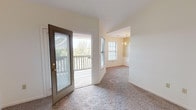 This single-floor residence at Georgetown Oaks Apartments offers a well-designed layout with several notable architectural features. The main living area is immediately impressive, boasting vaulted ceilings and a ceiling fan, with plush wall-to-wall carpeting underfoot. Natural light fills the space through multiple windows and a glass-paneled door that opens directly onto a private wooden deck, offering pleasant outdoor views.

The living area flows into a dedicated dining space, distinguished by an elegant chandelier and continued natural light from a multi-pane window. The galley-style kitchen is efficiently arranged with warm oak cabinetry, white appliances including a refrigerator and range, a built-in dishwasher, and a single-basin sink with a tile-style floor.

The bedroom areas are carpeted and bright, each featuring windows with blinds. The primary bedroom is generously proportioned with vaulted ceilings, a ceiling fan, and ample closet space. The bathroom is clean and functional, featuring a full tub-shower combination with chrome fixtures, tile flooring, a wood-toned vanity, and a medicine cabinet mirror. Overall, the unit presents a comfortable and practical living environment with classic finishes throughout.