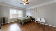 Located at 518 S 7th St in Tacoma, WA, this one-bedroom, one-bathroom unit blends classic architectural character with functional living. Rich hardwood flooring flows throughout the main living areas, complementing neutral gray walls and crisp white trim. A standout feature is the elegant arched doorway that connects the living space to the spacious bedroom, adding a timeless architectural detail to the interior.

The bedroom is generously proportioned, offering ample room for furnishings, and is brightened by a large window that allows natural light to fill the space. A ceiling fan overhead provides year-round comfort, and a cast-iron radiator adds to the classic charm. Two closets provide practical storage solutions.

The combined dining room and kitchen area is efficiently laid out, featuring an electric range and space for a dining setup. The bathroom is clean and well-appointed, featuring a pedestal sink, a toilet, a shower with curtain, and light vinyl flooring — all finished in a bright, white palette.

A hallway connects the rooms, providing a logical and comfortable flow throughout the unit. The overall ambiance is cozy yet refined, with period-appropriate details like arched passages and radiator heating paired with modern touches, making this Tacoma unit a practical and characterful place to call home.