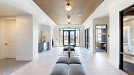 Located at 6090 US Highway 19 N in Palm Harbor, Florida, this thoughtfully designed single-floor commercial suite offers a refined and contemporary workspace. The welcoming reception area sets an immediate tone of sophistication, featuring a striking slatted wood ceiling, large-format tile flooring, and floor-to-ceiling black-framed glass entry doors that flood the space with natural light and views of the surrounding Florida landscape. Velvet ottomans and curated décor create an inviting first impression.

The interior transitions seamlessly between distinct functional zones. A central lounge and meeting area showcases terrazzo flooring, pendant lighting, and large windows overlooking the outdoors. A well-appointed kitchen and bar area features a waterfall-edge island with bar seating, designer pendant fixtures, a brick accent wall, tile panel backsplash, and a beverage center — ideal for team collaboration and client entertaining.

Nine private offices are thoughtfully distributed throughout the suite, several enclosed by sleek black-framed glass partitions for a balance of privacy and openness. Individual offices feature carpeted flooring, textured wall finishes, and floor-to-ceiling windows offering views of the lush exterior. Two closets and a full bathroom round out the accommodations, making this a fully functional and design-forward professional environment.