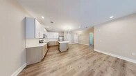 Located at 717 Preakness Avenue in Totowa, New Jersey, this thoughtfully designed residence offers a generous single-floor layout with 1 bedroom, 2 full bathrooms, and a spacious open-concept living area. The heart of the home is a modern kitchen equipped with stainless steel appliances, sleek white upper cabinetry paired with warm wood-toned lower cabinets, quartz countertops, and a central island with a sink — ideal for both cooking and casual dining. The kitchen flows seamlessly into the dining and living areas, all unified by light-toned hardwood-style flooring and recessed lighting, creating a bright and airy ambiance. Statement sputnik chandeliers add a contemporary touch throughout the common areas. The spacious primary bedroom features plush carpeting, crown molding, and access to a walk-in closet with built-in shelving. The bathrooms are finished with large-format marble-style tile flooring, wood-tone vanities, quartz countertops, backlit mirrors, and glass-enclosed showers. Additional highlights include two closets, a dedicated laundry area, and a hallway connecting the private quarters. Neutral warm-beige walls and clean white trim lend a polished, move-in-ready feel throughout this well-appointed home.