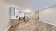 Located at 717 Preakness Avenue in Totowa, New Jersey, this thoughtfully designed residence offers a generous single-floor layout with 1 bedroom, 2 full bathrooms, and a spacious open-concept living area. The heart of the home is a modern kitchen equipped with stainless steel appliances, sleek white upper cabinetry paired with warm wood-toned lower cabinets, quartz countertops, and a central island with a sink — ideal for both cooking and casual dining. The kitchen flows seamlessly into the dining and living areas, all unified by light-toned hardwood-style flooring and recessed lighting, creating a bright and airy ambiance. Statement sputnik chandeliers add a contemporary touch throughout the common areas. The spacious primary bedroom features plush carpeting, crown molding, and access to a walk-in closet with built-in shelving. The bathrooms are finished with large-format marble-style tile flooring, wood-tone vanities, quartz countertops, backlit mirrors, and glass-enclosed showers. Additional highlights include two closets, a dedicated laundry area, and a hallway connecting the private quarters. Neutral warm-beige walls and clean white trim lend a polished, move-in-ready feel throughout this well-appointed home.
