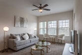 This single-floor residence offers a well-designed layout with a warm, neutral aesthetic throughout. The living area serves as the heart of the space, featuring plush carpeting, a ceiling fan, and an abundance of natural light streaming through multiple large windows with horizontal blinds. The open arrangement comfortably accommodates both a seating area and a dining nook, creating a versatile and inviting atmosphere.

The kitchen is outfitted with dark espresso cabinetry contrasted by light granite countertops and a subway tile backsplash. Stainless steel appliances, including a refrigerator, electric range with microwave, and dishwasher, provide modern functionality. Wood-look flooring runs throughout the kitchen, adding warmth and durability.

The bedroom is a tranquil retreat with carpet flooring, a ceiling fan, and a generously sized window that allows soft natural light to filter in. The room offers ample space for furnishings and provides a comfortable, restful environment.

The bathroom features dark wood cabinetry paired with a granite-topped vanity, a large mirror, and wood-look flooring. A shower-tub combination with a curtain rod completes the space. Overall, the residence presents a cohesive, contemporary design with practical finishes and a bright, airy ambiance.