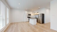 This single-story home in Waco, Texas offers a thoughtfully designed layout across a comfortable footprint. The open-concept living and kitchen area anchors the home, featuring light-toned luxury vinyl plank flooring that flows consistently throughout every room, creating a cohesive and airy aesthetic. Large windows and a glass-panel exterior door flood the living area with natural light and provide views of the surrounding greenery, complemented by a ceiling fan overhead.

The kitchen is well-appointed with white shaker cabinetry, dark granite countertops, a subway tile backsplash, and a full suite of stainless steel appliances including a refrigerator, range, microwave, and dishwasher. A central island with matching dark countertops provides additional workspace, while warm brass wall sconces add a refined finishing touch.

The two bedrooms are bright and functional, each featuring ceiling fans and windows with white blinds. A dedicated walk-in closet with built-in shelving and hanging rods serves one of the bedrooms, maximizing storage. The bathroom is finished with dark granite vanity countertops, white cabinetry, matte black hardware, and a glass-enclosed walk-in shower with white tile. Clean white walls and recessed lighting throughout contribute to the home's modern, minimalist character.