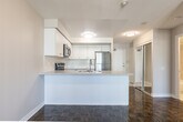 Located at 65 Times Ave in Markham, Ontario, this well-appointed one-bedroom, one-bathroom unit offers a thoughtfully designed single-floor layout. The open-concept kitchen and living area serves as the heart of the space, where the kitchen stands out with crisp white shaker cabinetry, stone-look countertops, a peninsula with a double stainless steel sink, and a full suite of stainless steel appliances including a refrigerator, electric range, over-the-range microwave, and dishwasher. White tile flooring grounds the kitchen, while rich parquet hardwood flooring extends through the living area and bedroom, adding warmth and character throughout.

The living room benefits from multiple windows that invite natural light and offer outdoor views, creating an airy and comfortable atmosphere. The bedroom is a well-proportioned retreat, featuring the same polished parquet flooring, a large window with an outdoor view, and a full-width sliding door closet providing ample storage. A mirrored closet near the entry further enhances the sense of openness.

The bathroom is finished with neutral floor-to-ceiling tile surrounding a full soaker tub and shower combination, offering a clean and functional design. Textured ceilings are consistent throughout the unit, adding a subtle architectural detail to the overall aesthetic.
