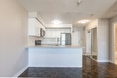 Located at 65 Times Ave in Markham, Ontario, this well-appointed one-bedroom, one-bathroom unit offers a thoughtfully designed single-floor layout. The open-concept kitchen and living area serves as the heart of the space, where the kitchen stands out with crisp white shaker cabinetry, stone-look countertops, a peninsula with a double stainless steel sink, and a full suite of stainless steel appliances including a refrigerator, electric range, over-the-range microwave, and dishwasher. White tile flooring grounds the kitchen, while rich parquet hardwood flooring extends through the living area and bedroom, adding warmth and character throughout.

The living room benefits from multiple windows that invite natural light and offer outdoor views, creating an airy and comfortable atmosphere. The bedroom is a well-proportioned retreat, featuring the same polished parquet flooring, a large window with an outdoor view, and a full-width sliding door closet providing ample storage. A mirrored closet near the entry further enhances the sense of openness.

The bathroom is finished with neutral floor-to-ceiling tile surrounding a full soaker tub and shower combination, offering a clean and functional design. Textured ceilings are consistent throughout the unit, adding a subtle architectural detail to the overall aesthetic.