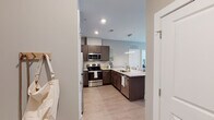 Located at 921 Trailwood Dr in Raleigh, NC, this single-floor residence offers a thoughtfully designed layout with modern finishes and a cohesive aesthetic throughout. The open-concept kitchen serves as a central highlight, featuring dark espresso cabinetry, light granite countertops, and a full suite of stainless steel appliances including a refrigerator, electric range, microwave, and dishwasher. A peninsula with pendant lighting and seating for multiple bar stools connects the kitchen to the living area, making it well-suited for both everyday use and entertaining. Light wood-style flooring flows through the main living spaces, complementing the neutral gray wall tones.

The living area receives natural light through large windows fitted with horizontal blinds and floor-length curtains, with a glass-panel door providing additional brightness. The bedroom is carpeted for comfort and features multiple windows that allow ample natural light, creating a calm and restful atmosphere. A spacious walk-in closet outfitted with wire shelving and hanging rods provides generous storage.

The bathrooms echo the kitchen's design language, incorporating matching dark cabinetry, granite-topped vanities, and wood-style flooring. One bathroom includes a glass-enclosed shower, while another features natural light from a large window, enhancing the overall sense of openness throughout the home.