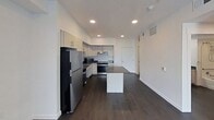 Located at 3993 South Main Street in Millcreek, UT, this 640-square-foot, one-bedroom, one-bathroom apartment delivers a clean, modern aesthetic across a single floor. Dark hardwood-style flooring runs throughout the unit, providing a cohesive contrast against the crisp white walls and ceilings fitted with recessed lighting. The kitchen is a standout feature, equipped with stainless steel appliances including a refrigerator, range, and microwave, complemented by light wood cabinetry, dark countertops, and a central island offering additional prep space. The open layout connects the kitchen seamlessly to the living area, maximizing the sense of space. The 170-square-foot bedroom is bright and airy, featuring a ceiling fan with light fixture and a large window with blinds that invites natural light. The bathroom includes an accessible-design vanity with dark countertop, a large mirror, and a combination tub and shower. A dedicated laundry room houses a full-size washer and dryer along with built-in shelving and closet rod storage, adding practical functionality. The unit's contemporary design, efficient layout, and quality finishes make it a well-appointed living space in the Millcreek area.
